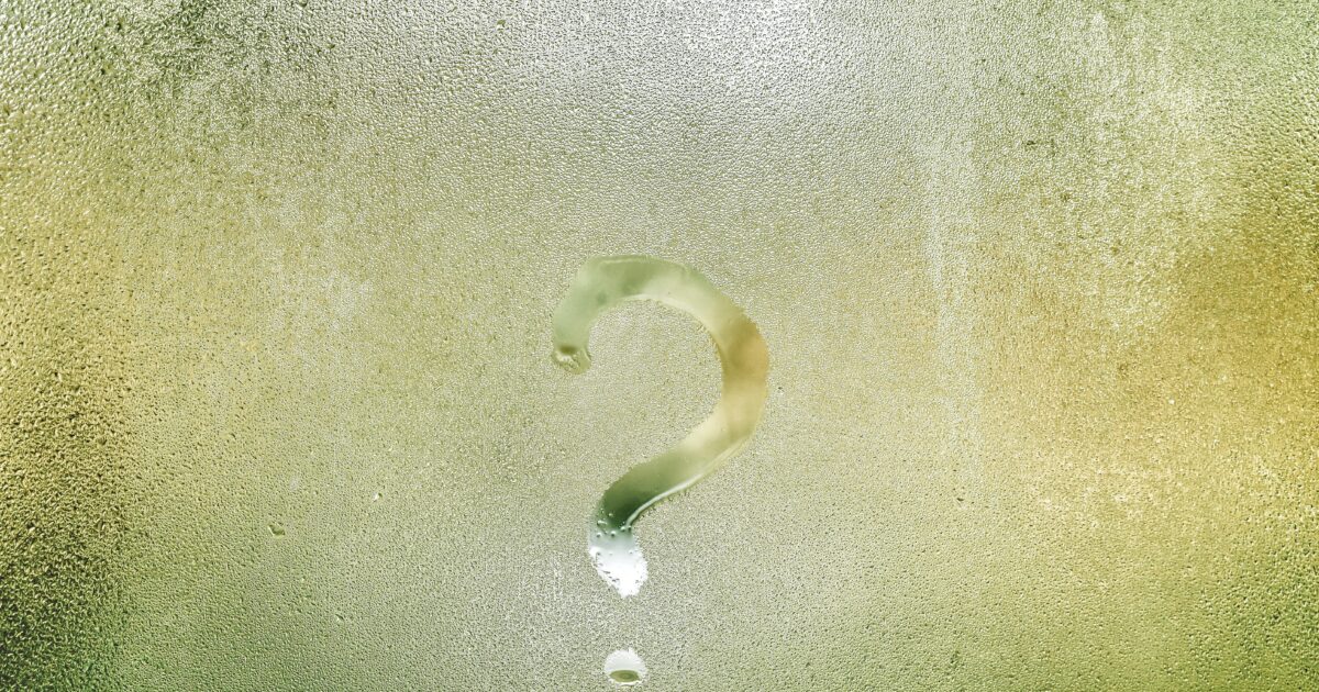 Photo d'un point d'interrogation tracé avec le doigt sur une vitre recouverte de buée