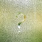 Photo d'un point d'interrogation tracé avec le doigt sur une vitre recouverte de buée