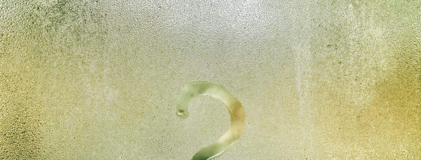 Photo d'un point d'interrogation tracé avec le doigt sur une vitre recouverte de buée