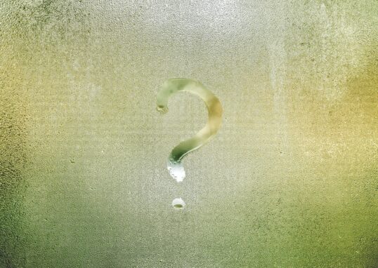 Photo d'un point d'interrogation tracé avec le doigt sur une vitre recouverte de buée