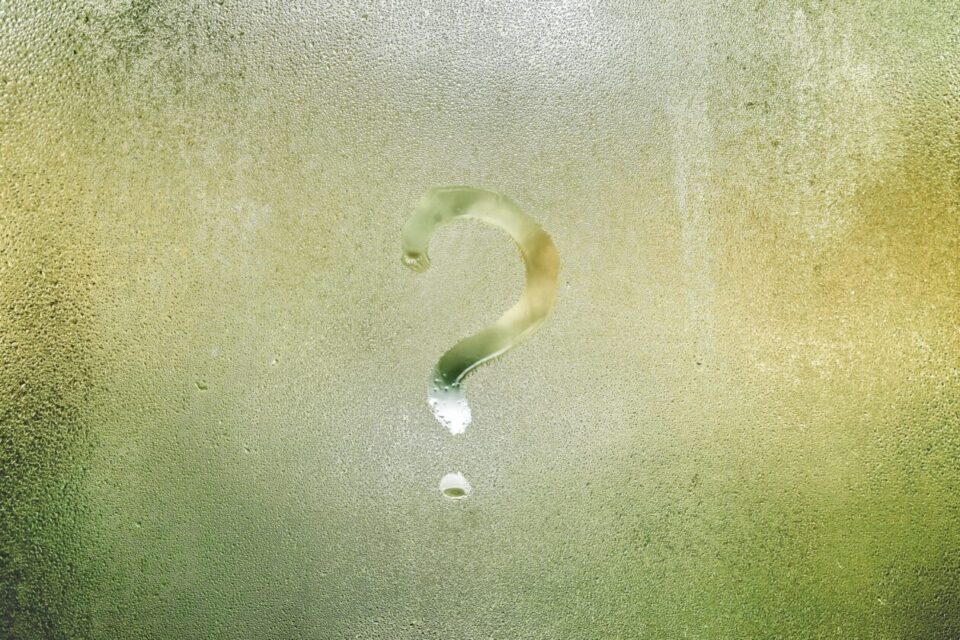 Photo d'un point d'interrogation tracé avec le doigt sur une vitre recouverte de buée