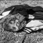 Photo de vêtements abandonnés sur un terrain vague. On voit un T-Shirt avec le visage d'un rappeur.